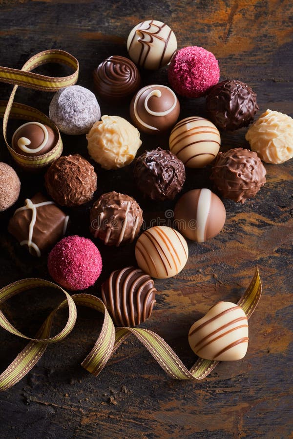 Valentínsky luxus čokoláda alebo výber dekoratívne ručné cukríky a zatočil stuha jediný srdce v tvare čokoláda zobrazené vysoký uhol.