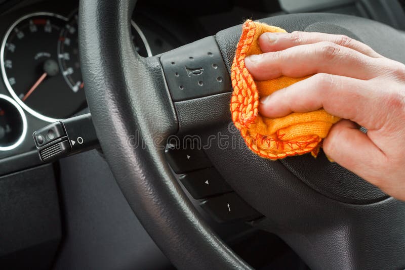 Polishing the car interior steering wheel with yellow duster. Polishing the car interior steering wheel with yellow duster