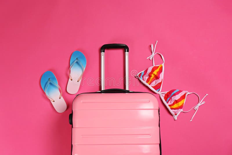 Valigia, cima di bikini e Flip-flop alla moda sul fondo di colore fotografie stock Valigia, cima di bikini e Flip-flop alla moda sul fondo di colore fotografie stock