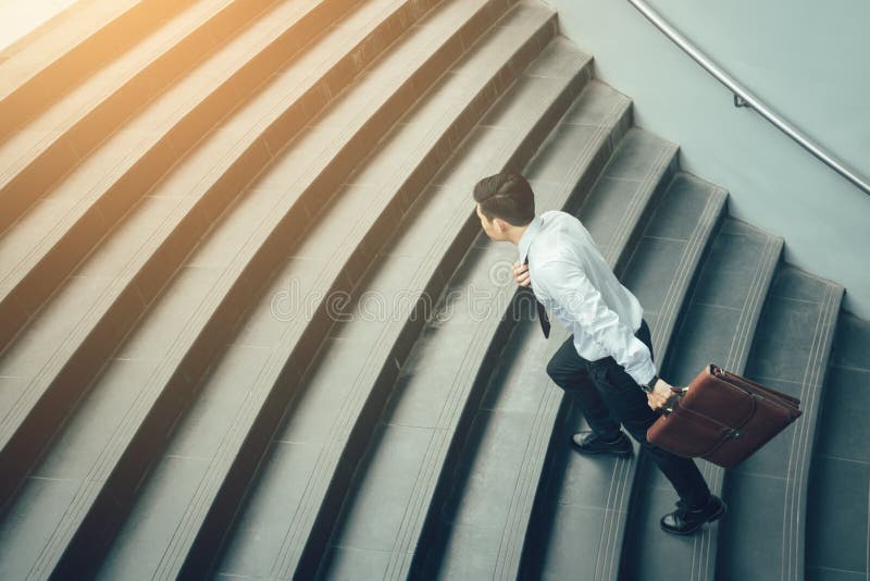Valigia e funzionamento della tenuta dell'uomo d'affari sulle scale immagini stock libere da diritti Valigia e funzionamento della tenuta dell'uomo d'affari sulle scale immagini stock libere da diritti