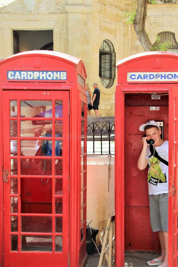 Valletta, Malta, im Juli 2016 Ein netter Junge spricht am Telefon in einer typischen englischen Telefonzelle stockfotografie Valletta, Malta, im Juli 2016 Ein netter Junge spricht am Telefon in einer typischen englischen Telefonzelle stockfotografie