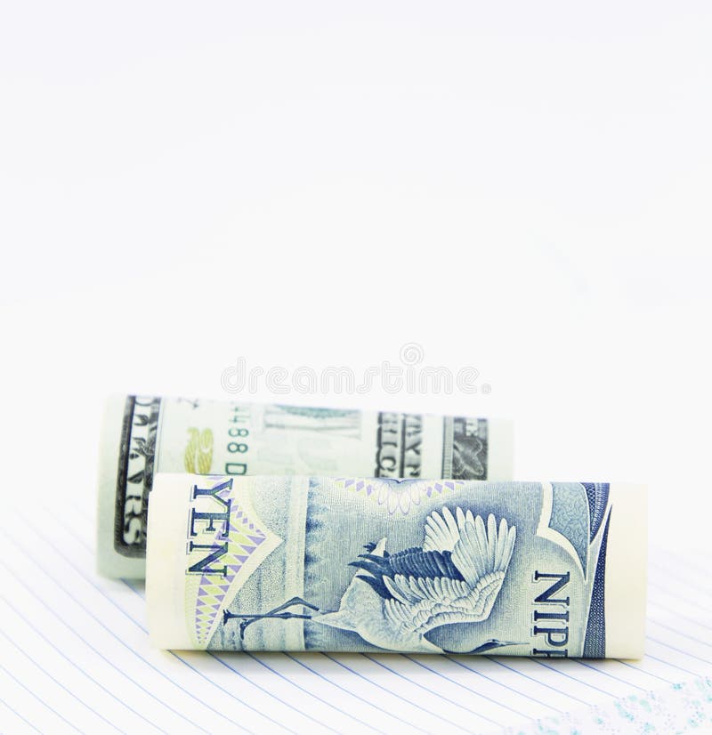 On a notebook with lined pages, two currencies, the dollar and yen, are positioned together in close up image. On a notebook with lined pages, two currencies, the dollar and yen, are positioned together in close up image