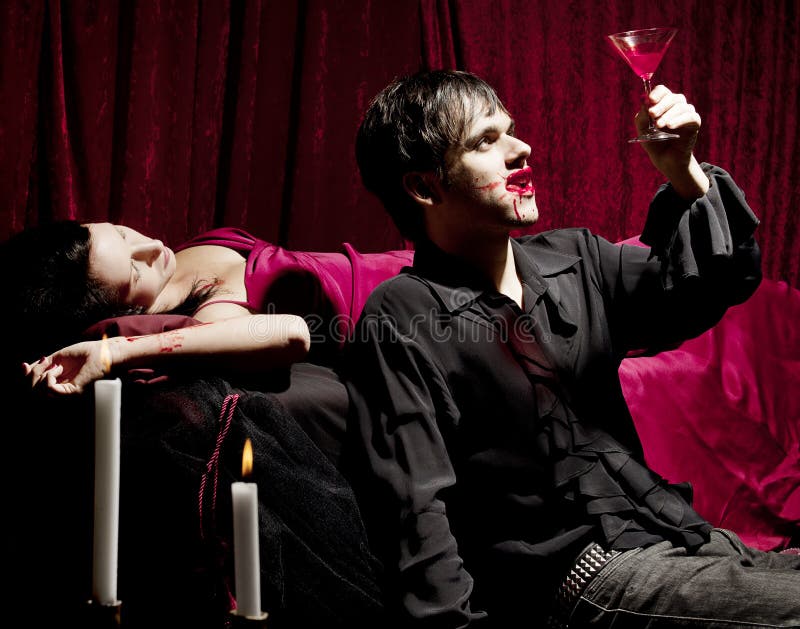 Vampiro che gode di una bevanda sanguinante immagini stock libere da diritti Vampiro che gode di una bevanda sanguinante immagini stock libere da diritti