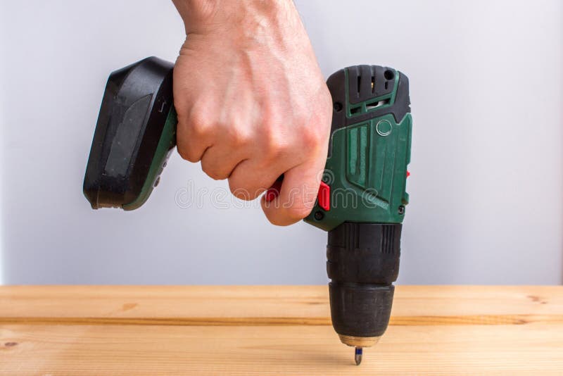 Van de de handholding van mensen de batterijboor en borings houten raad royalty-vrije stock afbeelding Van de de handholding van mensen de batterijboor en borings houten raad royalty-vrije stock afbeelding