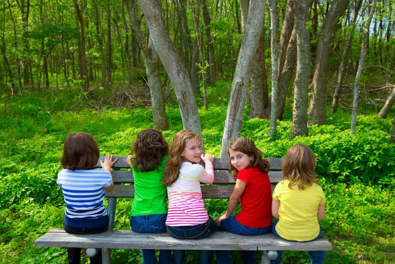 Children sister and friend girls sitting on park bench looking at forest and smiling. Children sister and friend girls sitting on park bench looking at forest and smiling