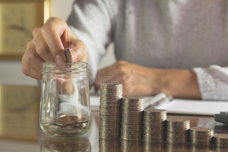 Van de vrouwenproces en daling muntstuk in het glas met stapelmuntstukken stock foto Van de vrouwenproces en daling muntstuk in het glas met stapelmuntstukken stock foto