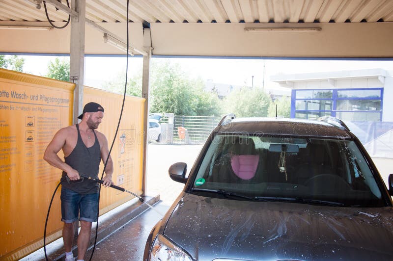 Van de de wasauto ` s van de mensenarbeider de legeringswielen bij de autowasserette royalty-vrije stock afbeelding Van de de wasauto ` s van de mensenarbeider de legeringswielen bij de autowasserette royalty-vrije stock afbeelding