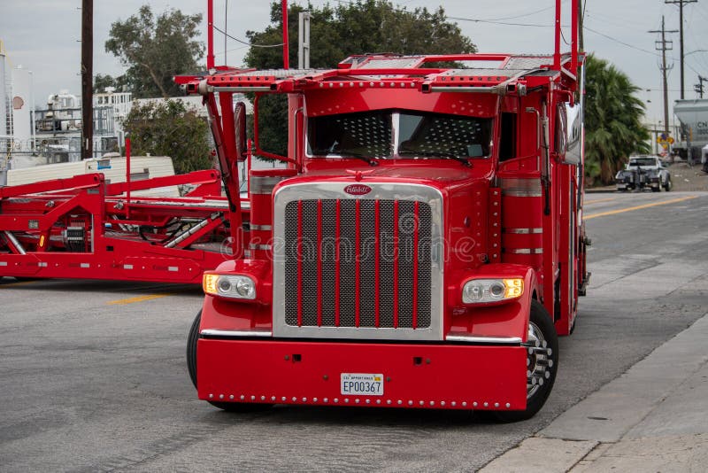 Van Nuys, California / USA  - January 20, 2020: A red Peterbuilt truck car-carrier owned by Pete`s Auto Transport making a wide turn in front of the Budweiser Brewery Gate 2