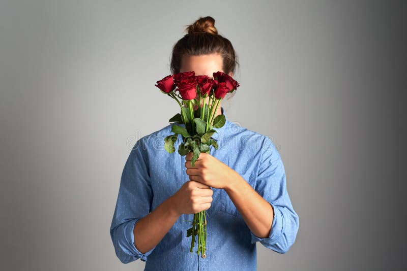 From your secret admirer. Studio shot of an unrecognizable man holding flowers against a grey background. From your secret admirer. Studio shot of an unrecognizable man holding flowers against a grey background