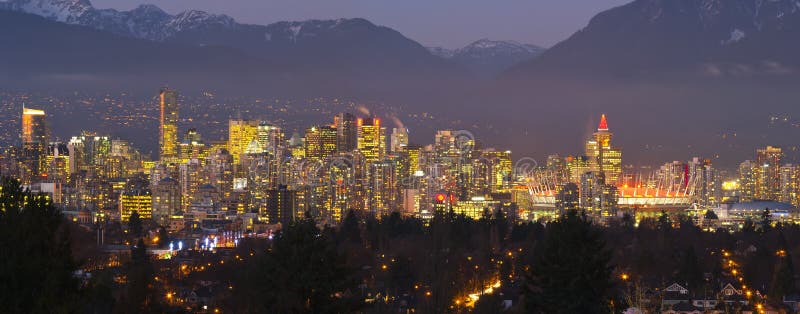 A panorama of Vancouver skyline in the evening, local mountains in the background.