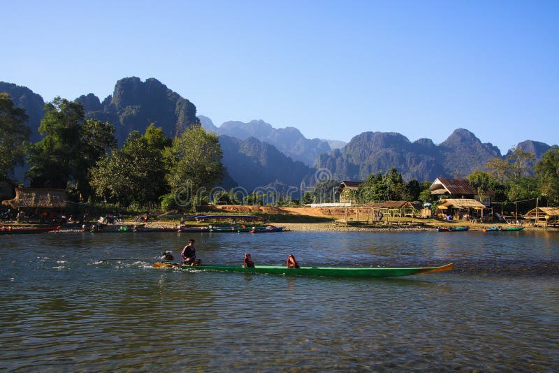 VANG VIENG, ЛАОС - 22-ОЕ ДЕКАБРЯ 2017: Сценарный взгляд над рекой на деревне окруженной ландшафтом холмов karst вдоль песни Xong стоковое фото VANG VIENG, ЛАОС - 22-ОЕ ДЕКАБРЯ 2017: Сценарный взгляд над рекой на деревне окруженной ландшафтом холмов karst вдоль песни Xong стоковое фото