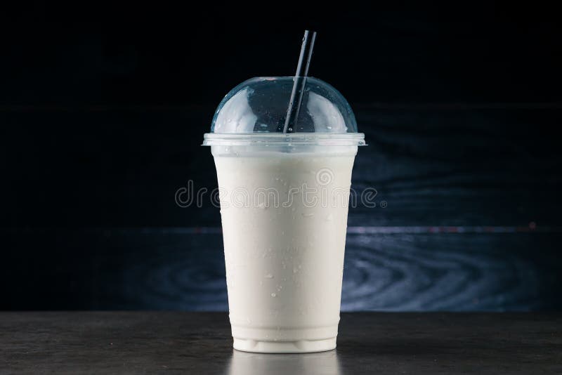 Vanilla Milkshake in Plastic Glass on a Dark Background. Vanilla