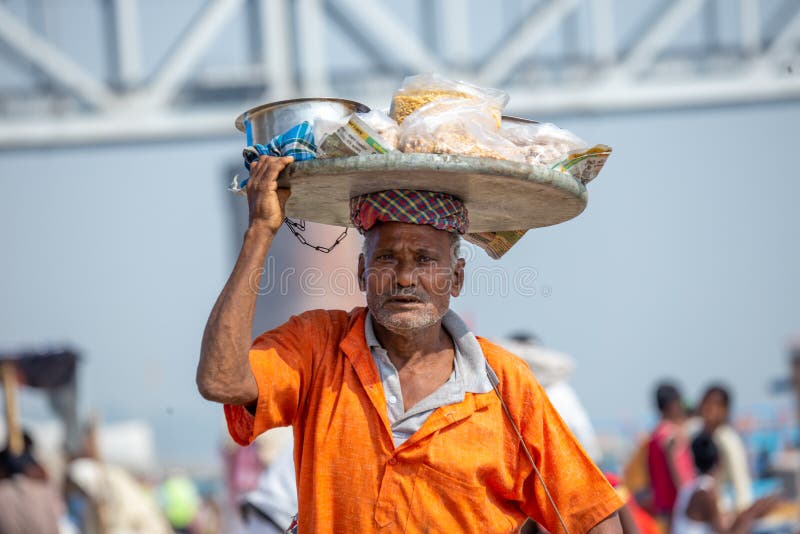 Varanasi, Índia, 18 de novembro de 2019/Homem indiano, vendedor de árvores, caminhando com um cesto de mercadorias na sua cabeça fotos de stock royalty free Varanasi, Índia, 18 de novembro de 2019/Homem indiano, vendedor de árvores, caminhando com um cesto de mercadorias na sua cabeça fotos de stock royalty free