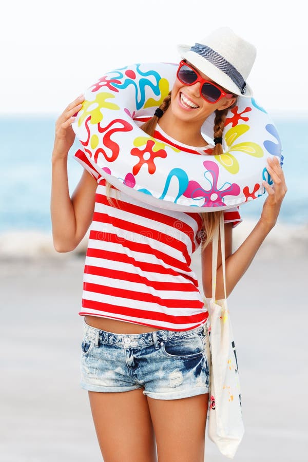 Vare la mujer feliz y las gafas de sol coloridas y el sombrero de la playa que llevan que se divierte el verano durante vacacione foto de archivo