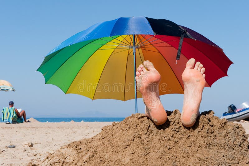 Beach vacation in the summer with bare feet and parasol in the sand. Beach vacation in the summer with bare feet and parasol in the sand