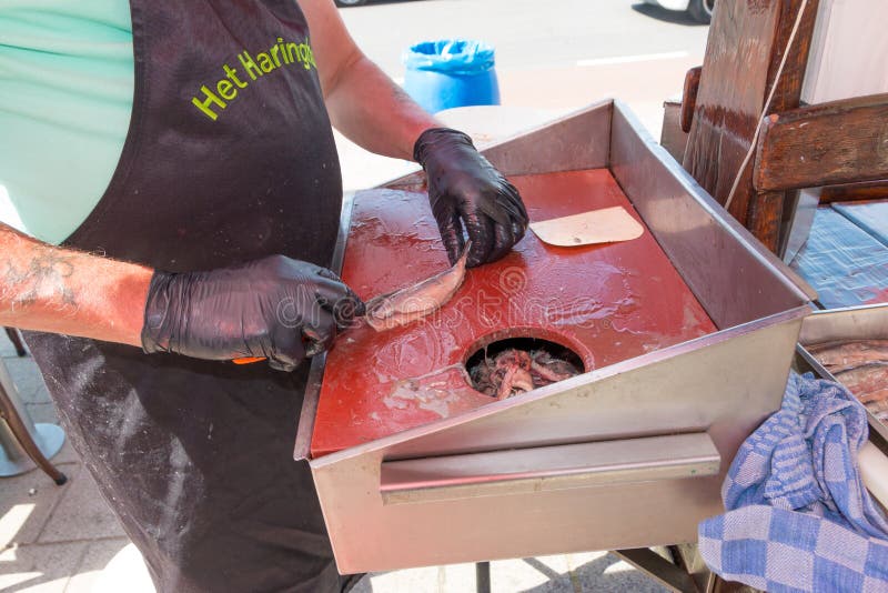 Varejista dos peixes que limpa arenques novos da estação para comer em sua tenda da loja fotos de stock Varejista dos peixes que limpa arenques novos da estação para comer em sua tenda da loja fotos de stock