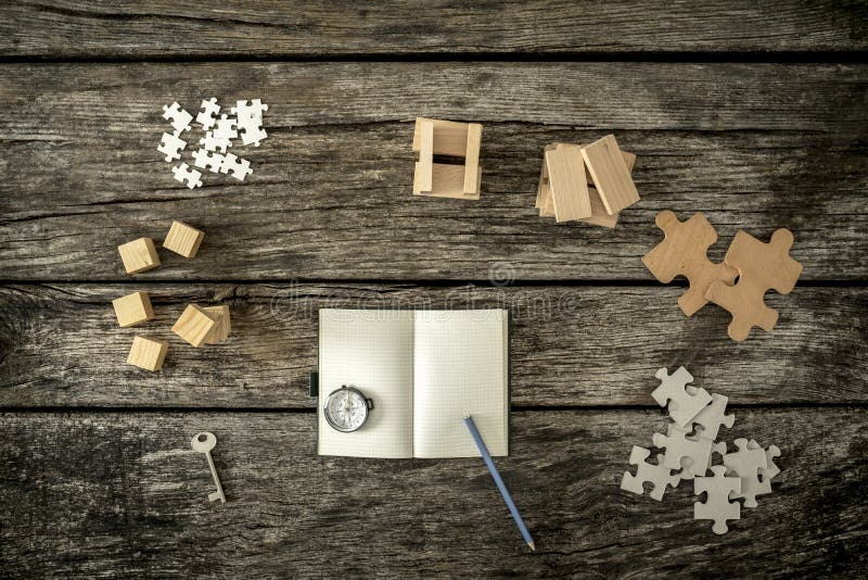 Vari cubi, pioli, puzzle e una chiave che si trova sul arou di legno dello scrittorio fotografia stock