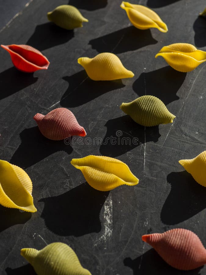 Vari tipi di pasta colorata. modello di pasta di diversi colori su uno sfondo nero. la pasta di colore giallo verde e rosso è composta da uno schema.