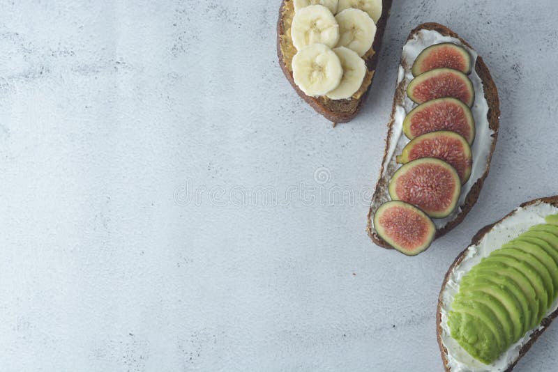 Variación de los bocadillos sanos del desayuno con el aguacate, el pepino, la fruta del higo, el plátano, el queso cremoso y el p fotografía de archivo Variación de los bocadillos sanos del desayuno con el aguacate, el pepino, la fruta del higo, el plátano, el queso cremoso y el p fotografía de archivo