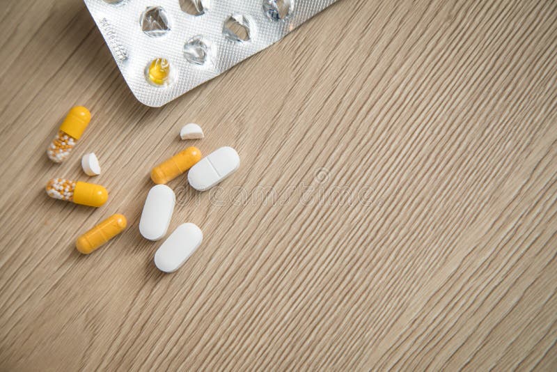 Variedad de tabletas amarillas y blancas medicina y ampolla de las píldoras en fondo de madera con el espacio de la copia foto de archivo libre de regalías Variedad de tabletas amarillas y blancas medicina y ampolla de las píldoras en fondo de madera con el espacio de la copia foto de archivo libre de regalías