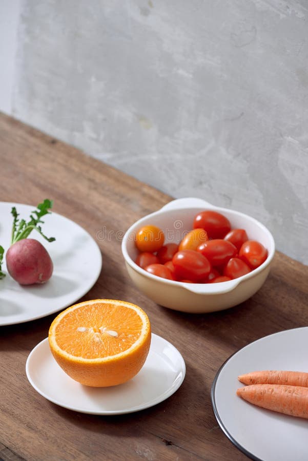 Variedade de ingredientes em um prato, no tomate cinzento da laranja, da cenoura, do rabanete e de ameixa fotos de stock Variedade de ingredientes em um prato, no tomate cinzento da laranja, da cenoura, do rabanete e de ameixa fotos de stock