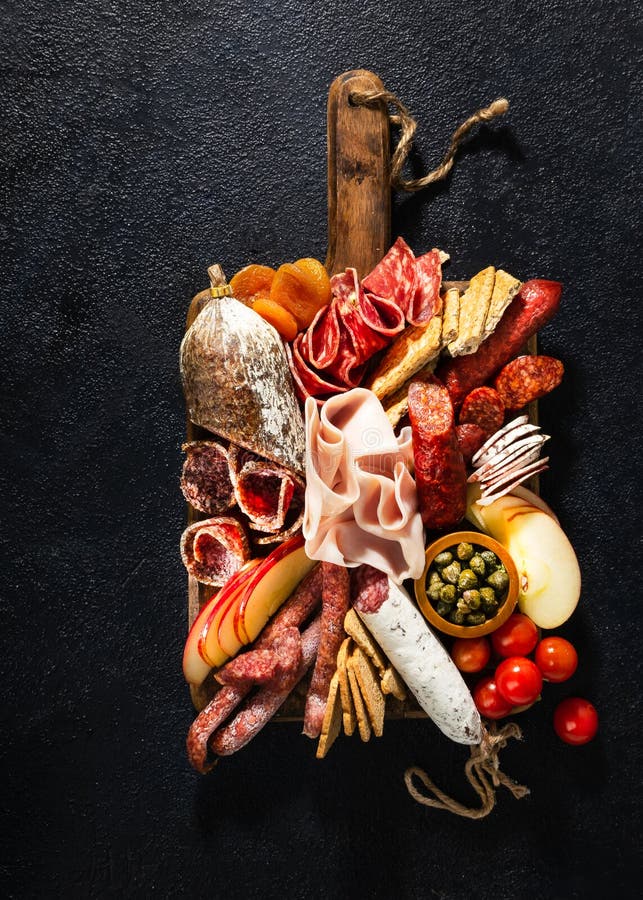 Variedade do salame e dos petiscos Salsicha Fouet, salsichas, salame, paperoni Em um fundo de madeira preto Vista superior Espa?o fotos de stock Variedade do salame e dos petiscos Salsicha Fouet, salsichas, salame, paperoni Em um fundo de madeira preto Vista superior Espa?o fotos de stock