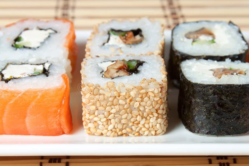 Variedade do sushi no prato branco sobre o fundo de bambu foto de stock Variedade do sushi no prato branco sobre o fundo de bambu foto de stock