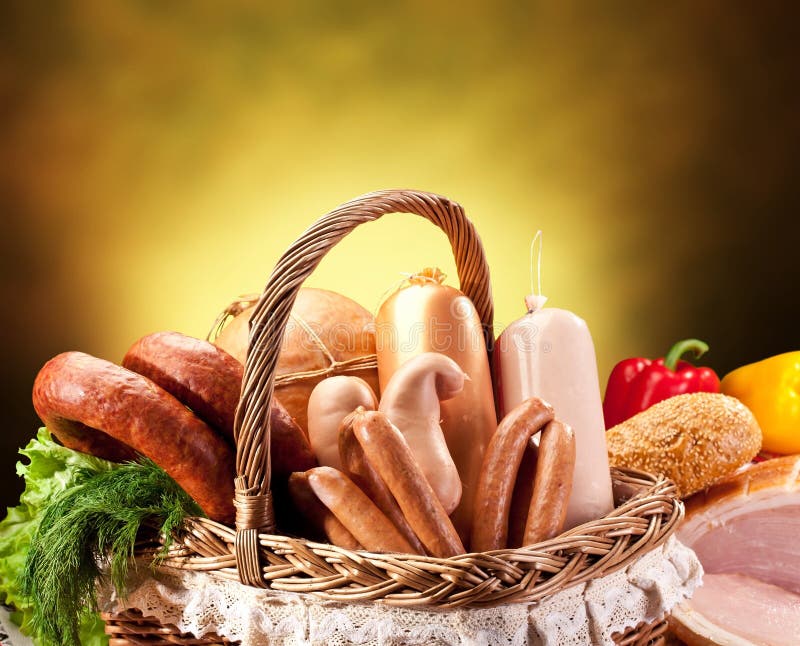 Variety of sausage products in the basket over brown background.