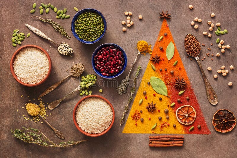 A variety of spices, cereals, beans, seeds on a dark background. Abstract christmas tree. Top view