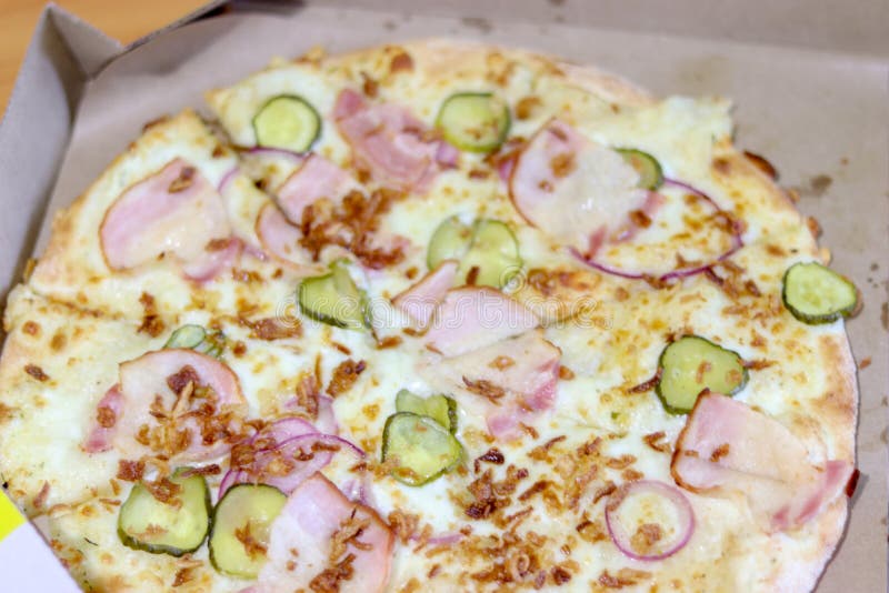 Varietà di condimenti: prosciutto, formaggio e sottaceti Pizza piccola in una scatola Consegna della pizza fresca e calda immagini stock Varietà di condimenti: prosciutto, formaggio e sottaceti Pizza piccola in una scatola Consegna della pizza fresca e calda immagini stock