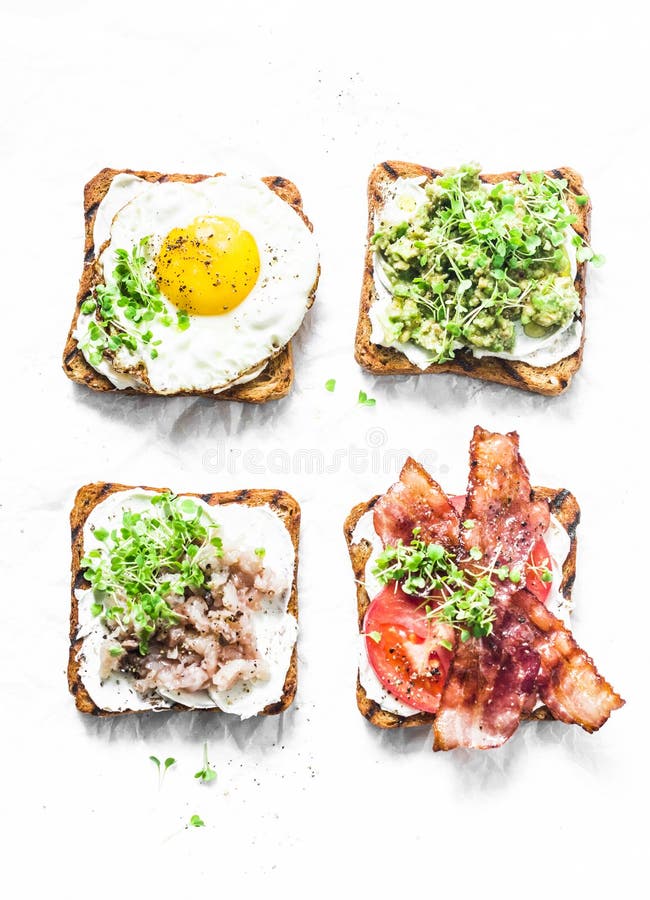 Varietà di panini per la prima colazione, spuntino, aperitivi - purè dell'avocado, uovo fritto, pomodori, bacon, formaggio cremos immagini stock Varietà di panini per la prima colazione, spuntino, aperitivi - purè dell'avocado, uovo fritto, pomodori, bacon, formaggio cremos immagini stock