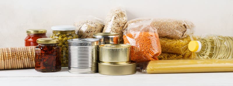 Various canned food and raw cereal grains on a table