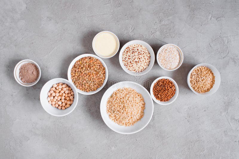 Various cereals and beans in white plates on gray textured table stock image Various cereals and beans in white plates on gray textured table stock image