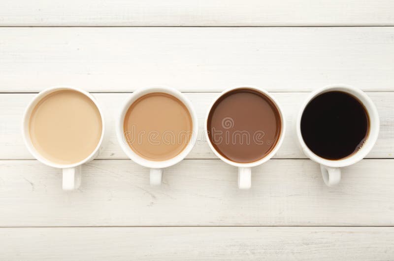 Various coffee cups on white wood, top view