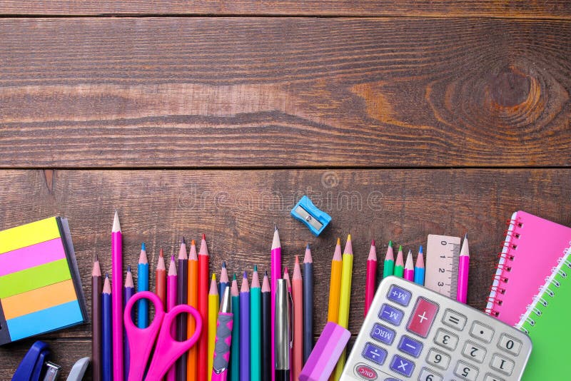 Various colorful school and office supplies on a brown wooden table.