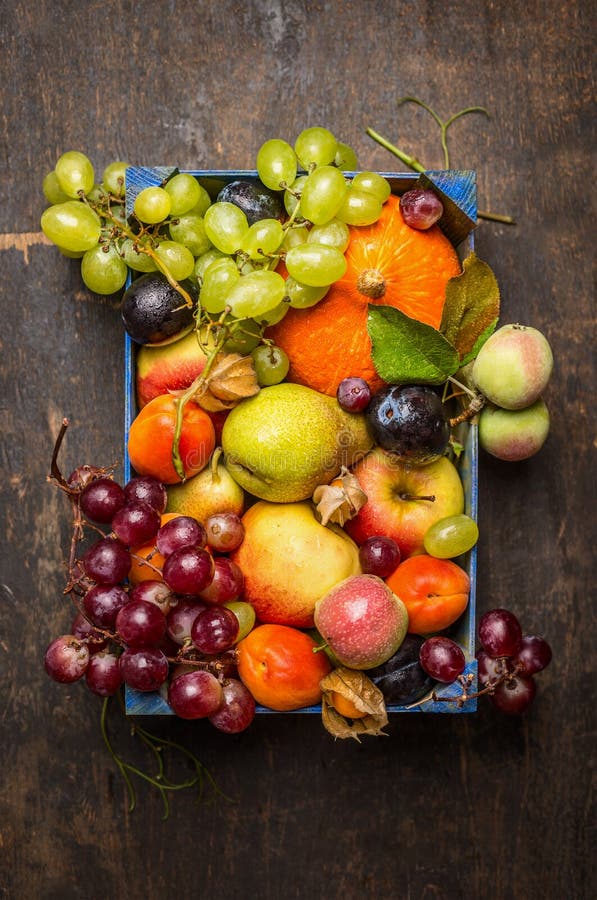Various fresh sharvest fruits in a blue box on a dark wooden texture, top view stock photo Various fresh sharvest fruits in a blue box on a dark wooden texture, top view stock photo