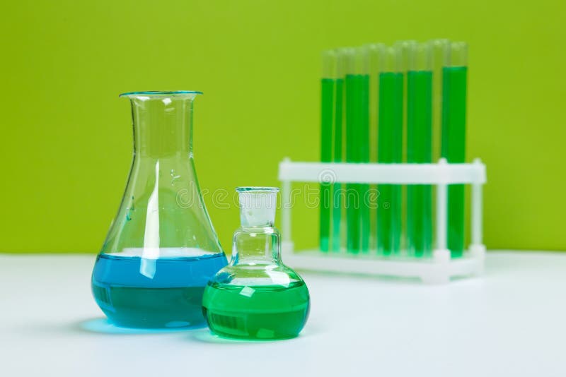 Various Laboratory Glass Items with Water and Empty on White Table with Green Background Stock
