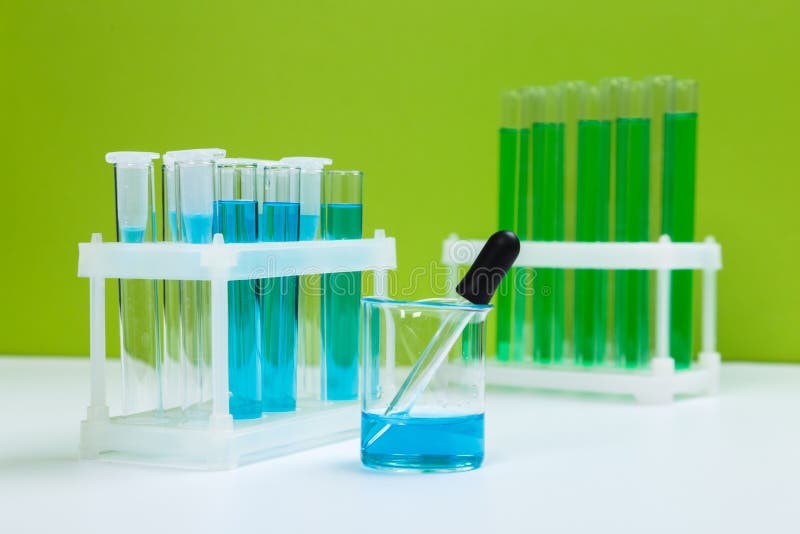 Various Laboratory Glass Items with Water and Empty on White Table with Green Background Stock