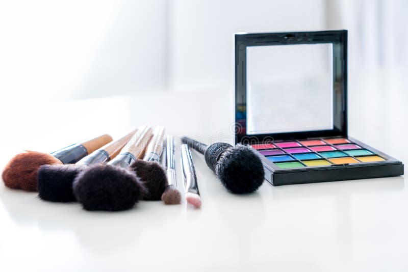 Various make up brush with make up products and concealers cosmetics on table in white background.