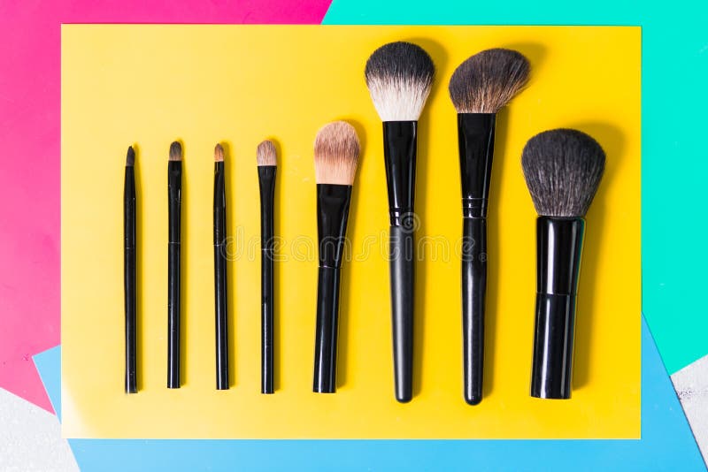 Various makeup brushes on a bright yellow background, close-up