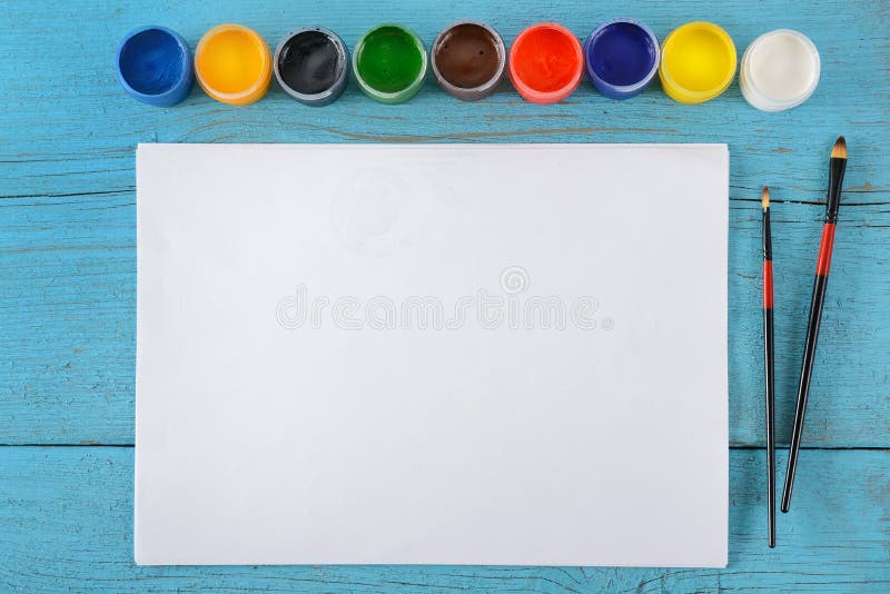 Various paints, brushes, white sheets paper on wooden blue background. Top view. royalty free stock photos