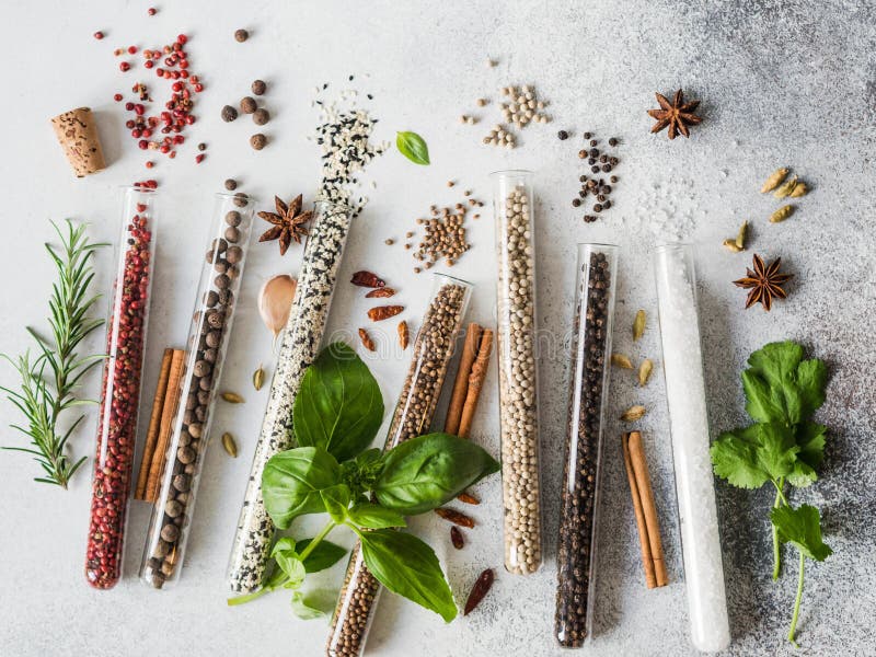 Various Spices in Glass Test Tubes and Fresh Herbs on Gray Background