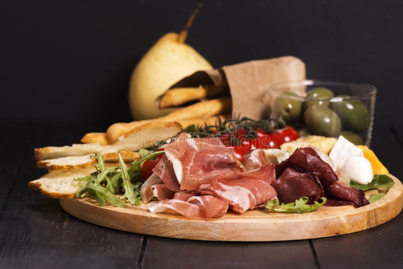 Various types of italian appetizers: ham, cheese, grissini, olives, fruits