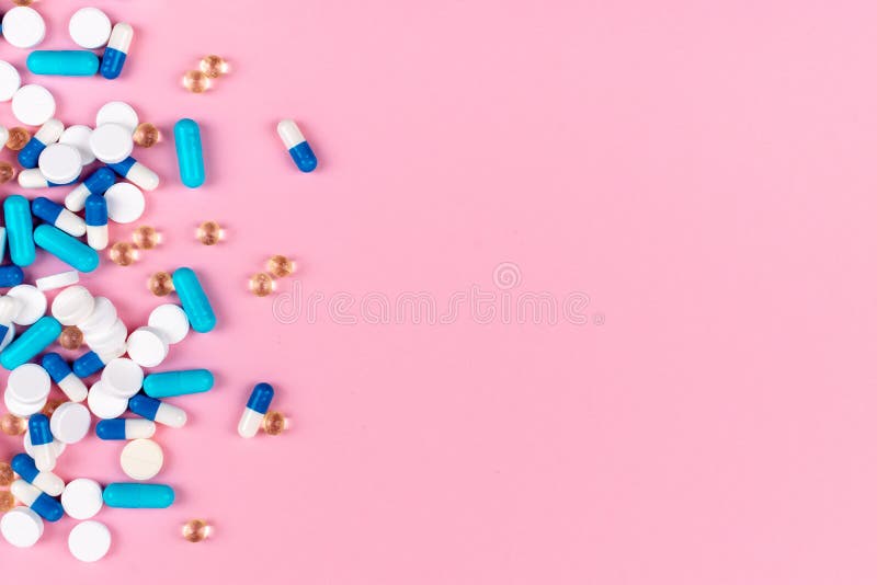 Various white and blue pills on pink background with copy space. Different medical drugs, tablets and pills. Flat lay, top view