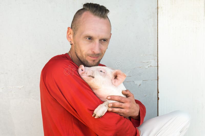 Varkenslandbouwer met leuk biggetje in handen bij landbouwbedrijfmuur Nadruk op piggy royalty-vrije stock afbeelding Varkenslandbouwer met leuk biggetje in handen bij landbouwbedrijfmuur Nadruk op piggy royalty-vrije stock afbeelding