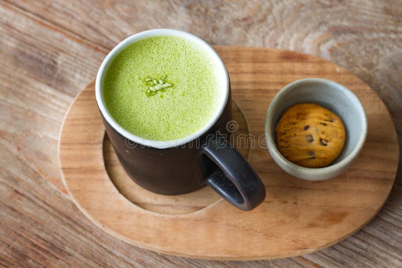 Varm bakgrund för trä för Greentea matchalatte arkivfoto