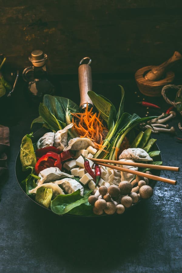 Varm kruka för smaklig vegetarisk asiatisk klimp Nya färgrika asiatiska matingredienser wokar in pannan med pinnar på mörkt lantl royaltyfria bilder