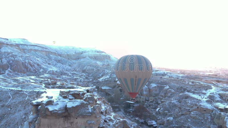 Varmluftsballonger som flyger över de grottor som täcks av snö i cappadocia