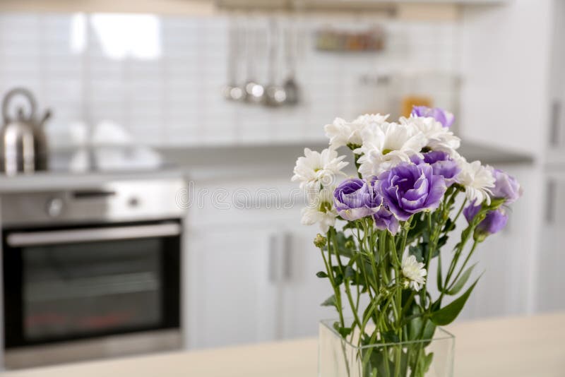 Vase with beautiful flowers in kitchen interior.