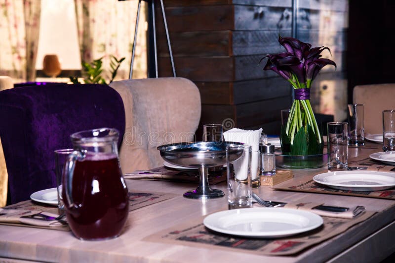 Vase with Purple Flowers on a Table in a Restaurant Interior. Stock